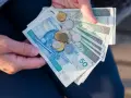 Ręce trzymają polskie banknoty i monety. Czy mam 60 lat i 10 lat pracy, czy dostanę emeryturę?