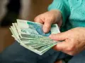 Dłonie starszej osoby liczą banknoty. Zastanawiasz się, ile wynosi dodatek do emerytury za warunki szkodliwe?