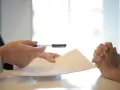 Dwie osoby przy stole omawiają dokumenty. Kluczowe pytanie brzmi: czy umowa zlecenie wlicza się do emerytury?
