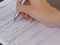 Ręka wypełnia kwestionariusz osobowy, wpisując dane dotyczące świadczenia wychowawczego.