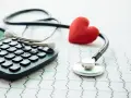 Stetoskop, kalkulator i czerwone serce na tle EKG symbolizują troskę o zdrowie i planowanie finansowe, w tym dobrowolne ubezpieczenie chorobowe.