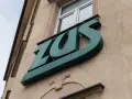 Zielone logo ZUS na budynku. To miejsce, gdzie można załatwić sprawy związane z ubezpieczeniem chorobowym.