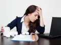Zmęczona kobieta z kubkiem i chusteczkami przy laptopie. Zastanawia się, ile można być na zwolnieniu lekarskim od psychiatry.