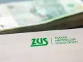 ZUS i stos banknotów. Pytanie o to, w jakim wieku renta na stałe, jest kluczowe dla przyszłości finansowej.