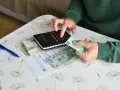 Ręce liczą pieniądze i dokumenty ZUS, przygotowując się do złożenia wniosku o rentę chorobową.