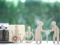 Skarbonka i drewniane figurki symbolizujące wsparcie dla osoby z niepełnosprawnością i seniorów.