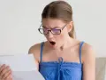 Zaskoczona kobieta w okularach czyta dokument. Czy to wypowiedzenie umowy zlecenia?