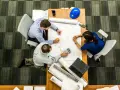 Trzech inżynierów, w tym project manager, analizuje plany na stole.