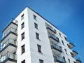 Nowoczesny budynek mieszkalny z balkonami i szklanymi balustradami, na tle błękitnego nieba. Idealne miejsce do życia, jak w pit 39.