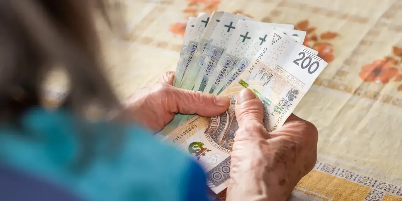 Dłonie starszej osoby liczą banknoty 200 zł. Tabela 14. emerytury może zawierać takie kwoty.