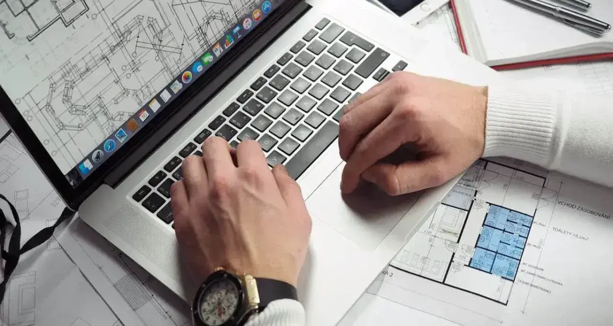 Architekt pracuje nad projektem na laptopie, analizując plany. Zastanawiasz się, ile zarabia architekt?