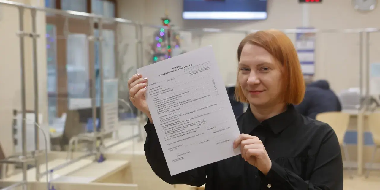 Kobieta trzyma w ręku wniosek o przyznanie dodatku mieszkaniowego.