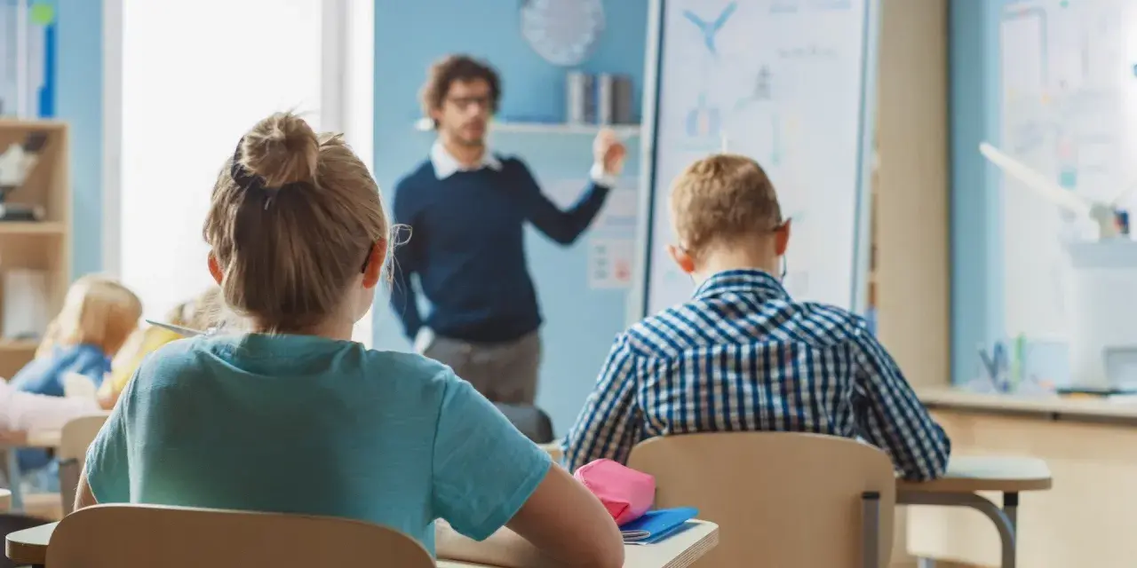 Nauczyciel tłumaczy lekcję, a uczniowie słuchają. Ciekawe, ile zarabia nauczyciel za taką pracę?
