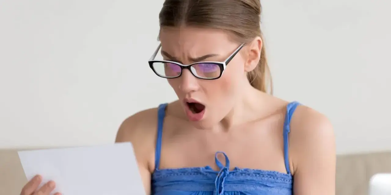 Zaskoczona kobieta w okularach czyta dokument. Czy to wypowiedzenie umowy zlecenia?