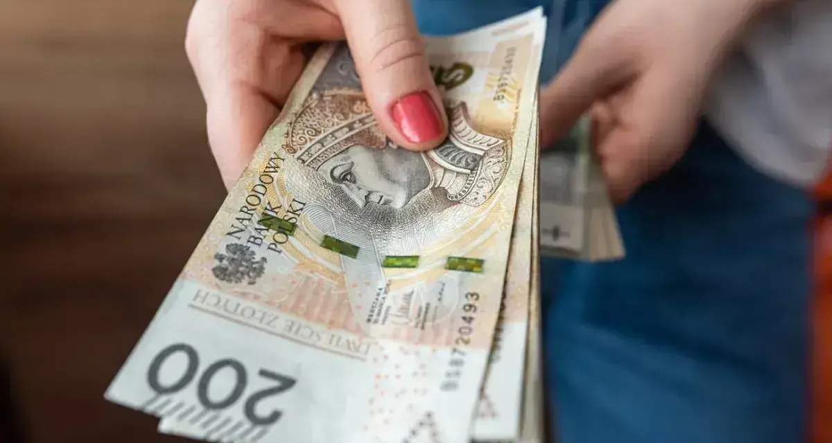 Dłoń trzyma stos banknotów 200 zł. Czekamy na przelew, kiedy ZUS robi przelewy, to zawsze radość.