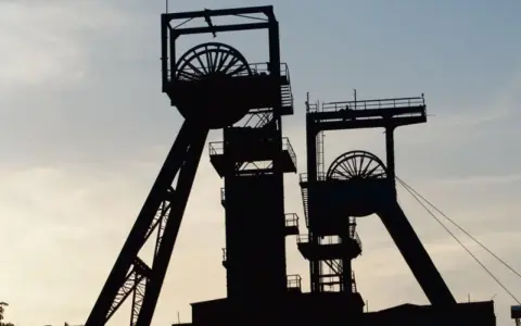 Dwie wieże szybowe kopalni węgla na tle nieba. Zastanawiasz się, ile zarabia górnik?