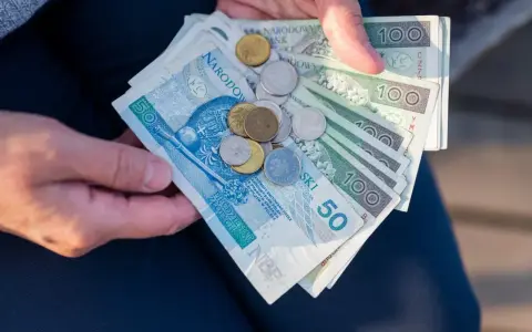 Ręce trzymają polskie banknoty i monety. Czy mam 60 lat i 10 lat pracy, czy dostanę emeryturę?
