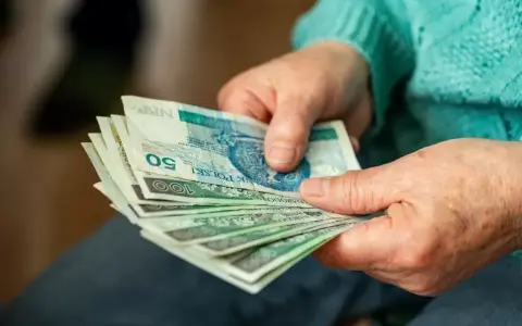 Dłonie starszej osoby liczą banknoty. Zastanawiasz się, ile wynosi dodatek do emerytury za warunki szkodliwe?