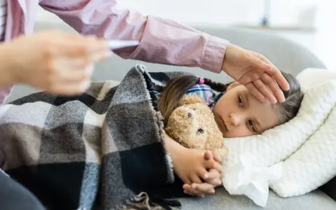 Chora dziewczynka z misiem pod kocem, mama mierzy jej temperaturę. ZUS 15a.