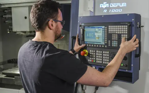 Operator CNC przy panelu sterowania. Dobra praca to wysokie operator cnc zarobki.