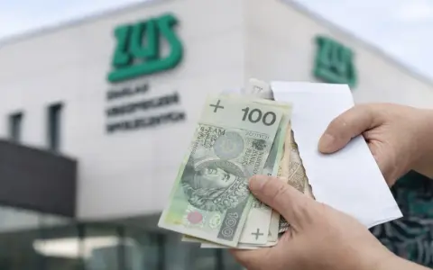 Ręce trzymają polskie banknoty przed budynkiem ZUS. To symboliczny moment, kiedy wypłata 14 emerytury staje się rzeczywistością.
