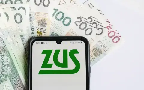 ZUS na ekranie telefonu, obok banknoty 100, 200 i 500 zł. Symbolizuje to zasiłek pogrzebowy 6000 zł.