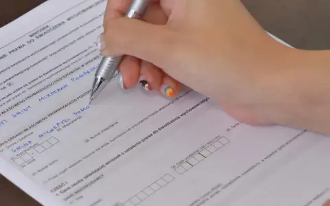 Ręka wypełnia kwestionariusz osobowy, wpisując dane dotyczące świadczenia wychowawczego.