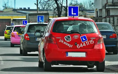 Czerwony samochód nauki jazdy z literą "L" na dachu. Zastanawiasz się, ile zarabia instruktor jazdy?
