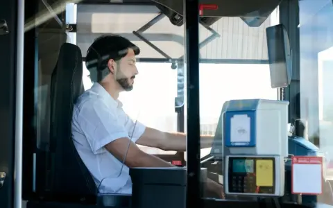 Mężczyzna za kierownicą autobusu, zastanawia się, ile zarabia kierowca autobusu.