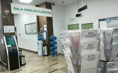 Sala obsługi klienta z terminalem, dystrybutorem wody i stojakami z formularzami ZUS, np. ZUA, ZZA, ZCNA. rp7.