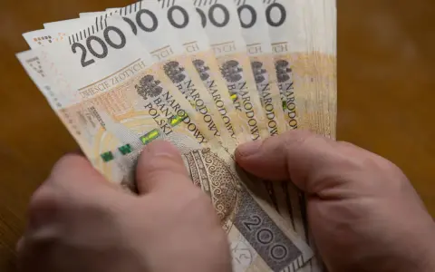 Dłonie trzymają stos banknotów po 200 zł. Czy to wystarczy, by poznać, ile wynosi najniższa krajowa netto?