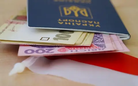 Ukraiński paszport z pieniędzmi, symbolizujący nadzieję na godną emeryturę dla Ukraińców w Polsce.
