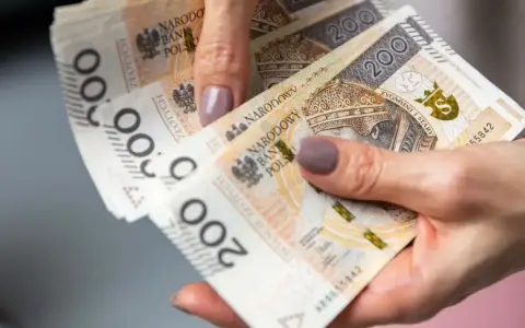 Dłoń trzyma stos banknotów 200 zł. To może być pożyczka od rodziny na nieprzewidziane wydatki.