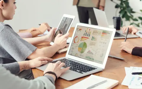 Analityk finansowy pracuje nad raportem na laptopie, analizując wykresy i dane.