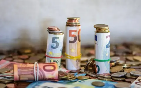 Zwijane banknoty euro i monety, symbolizujące kwotę darowizny wolną od podatku, tworzą stosy na tle innych monet.