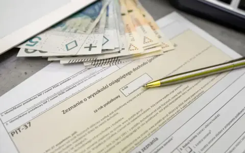 Pieniądze i formularz PIT-37. Zastanawiasz się, jaka jest kwota wolna od podatku? Długopis czeka na wypełnienie zeznania.
