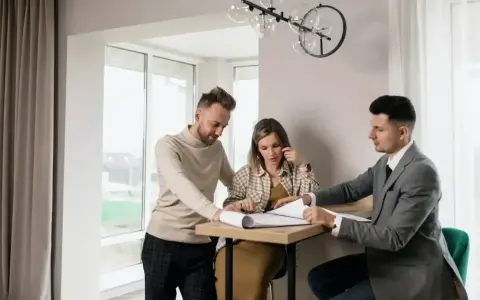 Para, która ogląda dokumenty z agentem nieruchomości, zastanawia się, ile zarabia agent nieruchomości.