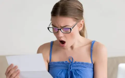 Zaskoczona kobieta w okularach czyta dokument. Czy to wypowiedzenie umowy zlecenia?