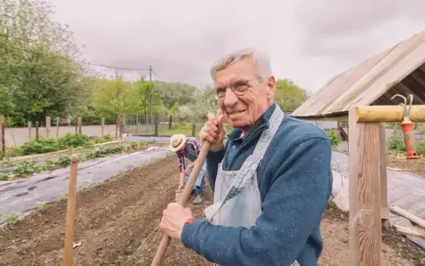 Uśmiechnięty starszy pan z łopatą w ręku, pracujący w ogrodzie. Zastanawia się, jaka emerytura z KRUS po 10 latach będzie mu przysługiwać.