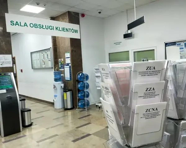 Sala obsługi klienta z terminalem, dystrybutorem wody i stojakami z formularzami ZUS, np. ZUA, ZZA, ZCNA. rp7.