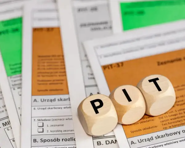 Drewniane klocki z literami "PIT" leżą na formularzach podatkowych. Temat: kwota wolna od podatku 2026.