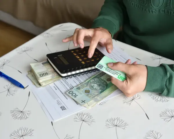 Ręce liczą pieniądze i dokumenty ZUS, przygotowując się do złożenia wniosku o rentę chorobową.