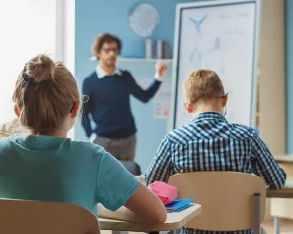 Nauczyciel tłumaczy lekcję, a uczniowie słuchają. Ciekawe, ile zarabia nauczyciel za taką pracę?