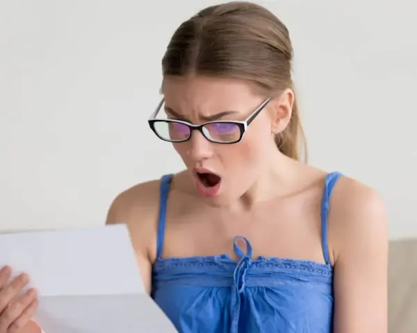 Zaskoczona kobieta w okularach czyta dokument. Czy to wypowiedzenie umowy zlecenia?