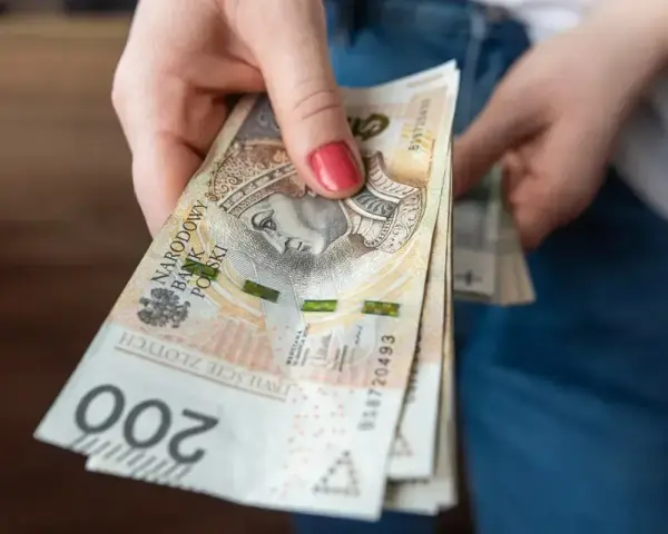 Dłoń trzyma stos banknotów 200 zł. Czekamy na przelew, kiedy ZUS robi przelewy, to zawsze radość.