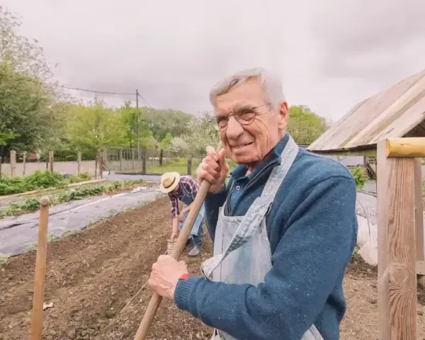 Uśmiechnięty starszy pan z łopatą w ręku, pracujący w ogrodzie. Zastanawia się, jaka emerytura z KRUS po 10 latach będzie mu przysługiwać.