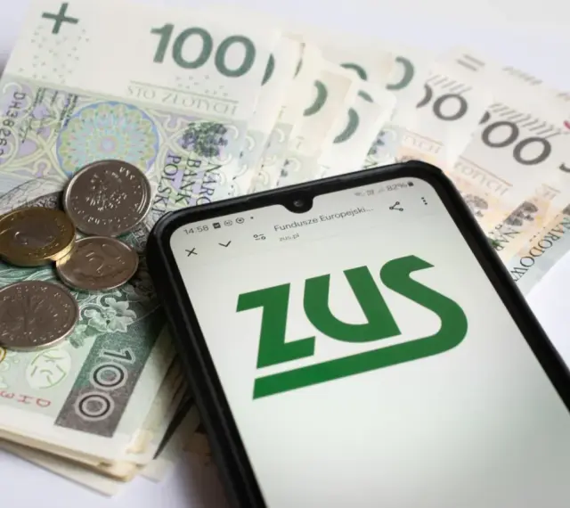 Na ekranie telefonu widnieje logo ZUS. Obok leżą polskie banknoty i monety. To może być druk z15 związany z finansami.
