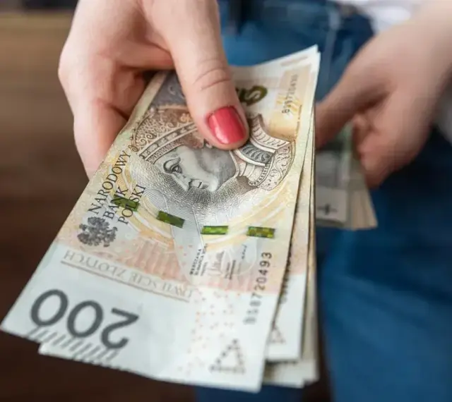 Dłoń trzyma stos banknotów 200 zł. Czekamy na przelew, kiedy ZUS robi przelewy, to zawsze radość.