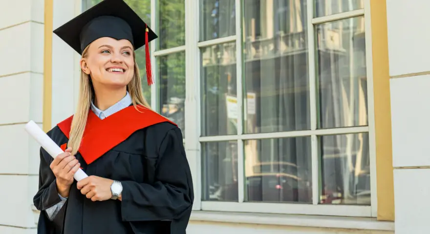 Uśmiechnięta absolwentka z dyplomem, w todze i birecie, zastanawia się, co to studia MBA i jakie możliwości otwierają.