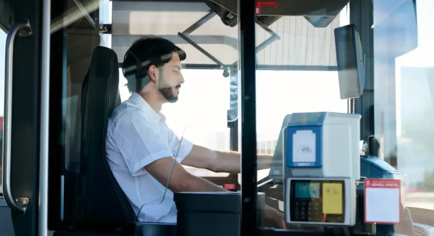 Mężczyzna za kierownicą autobusu, zastanawia się, ile zarabia kierowca autobusu.